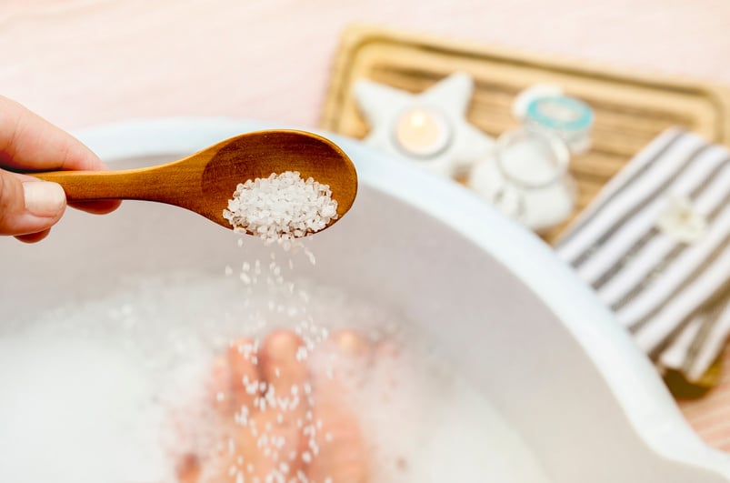 Adding Magnesium Chloride vitamin salt in foot bath water, solution. Magnesium grains in foot bath water are ideal for replenishing the body with this essential mineral, promoting overall well being.